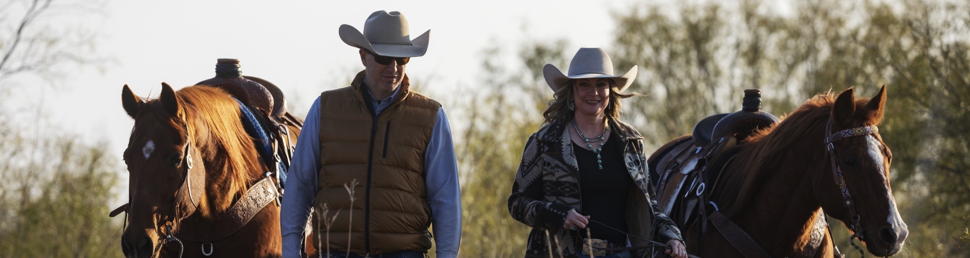 A Couple Wearing Western Gear Leading their Horses
