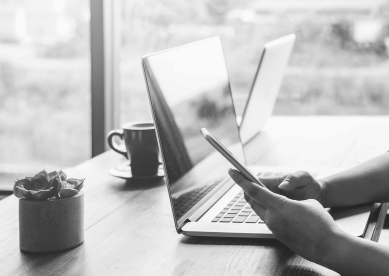 Person checking phone while they work on their laptop at a shared desk
